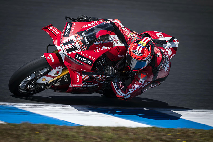 Nicolò Bulega cornering on the Ducati Panigale V4 R 2026 for Aruba.it Racing Ducati, wearing a helmet featuring the Magneti Marelli Checkstar logo